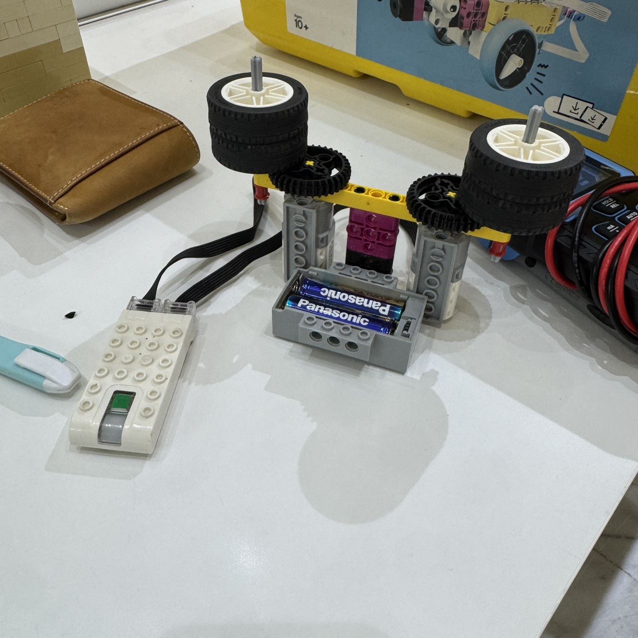 測試用積木：WeDo 2.0 主機接兩顆馬達，每顆馬達經 36–12 齒輪加速帶動兩顆輪胎空轉